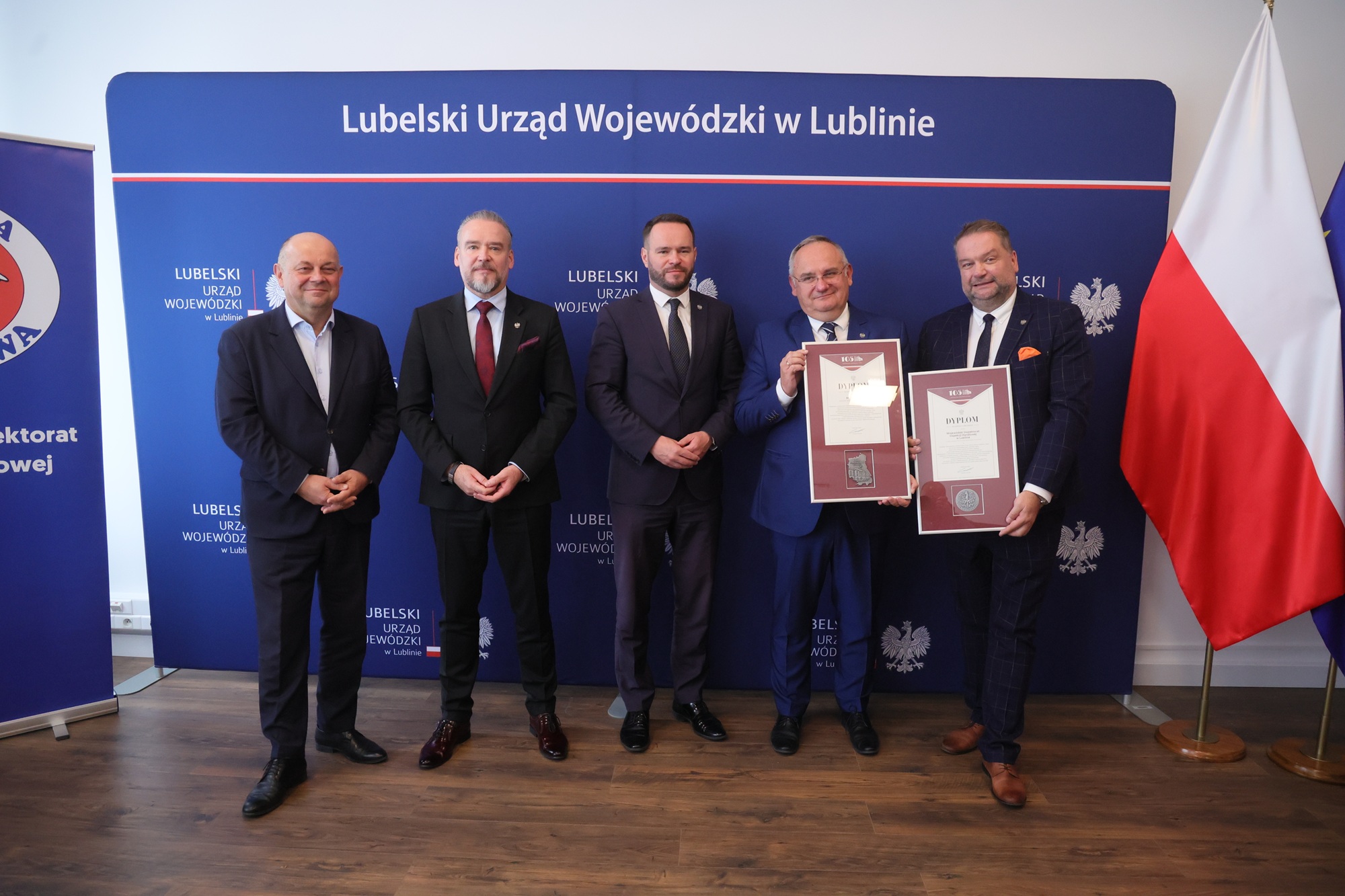 Zdjęcie grupowe, od lewej: Dyrektor Generalny Lubelskiego Urzędu Wojewódzkiego Jarosław Szymczyk, wicewojewoda Wojciech Wołoch, Wojewoda lubelski Krzysztof Komorski oraz z wręczonymi im dyplomami Wojewódzki Inspektor Marcin Zając i jego zastępca Mirosław Fatyga.