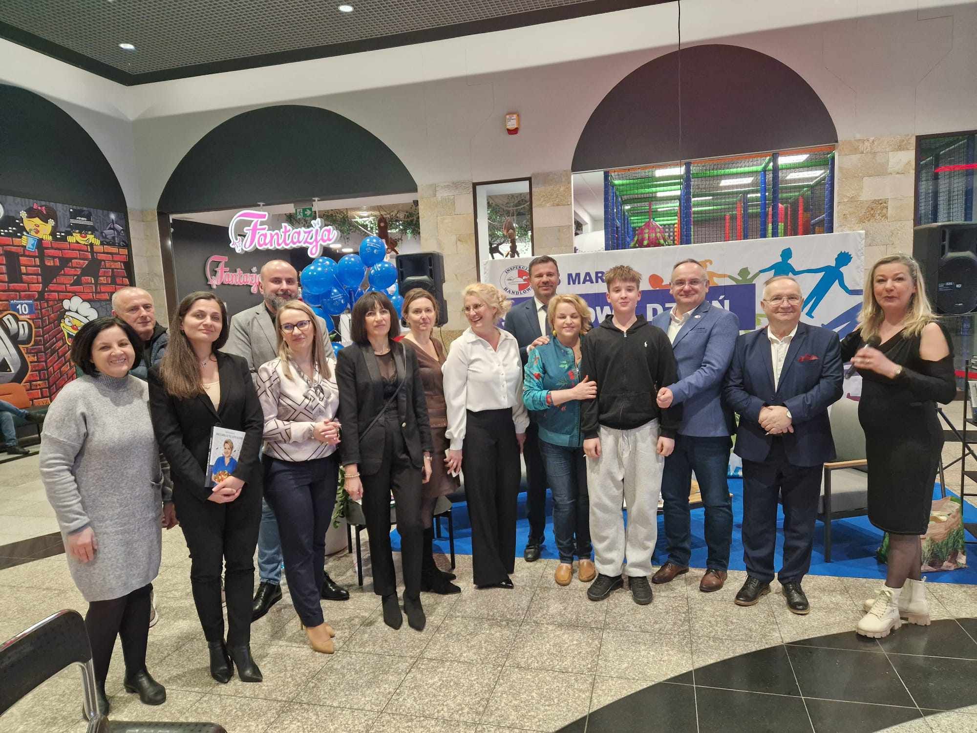 Organizatorki stoją obok Wojewódzkiego Inspektorem Inspekcji Handlowej w Lublinie Marcina Zająca. W centralnym miejscu prezydent Zamościa.